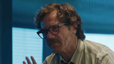 Guardedly.
Informally. - The Little Drummer Girl