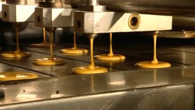 NEXT, EJECTOR NOZZLES SQUIRT THE
BATTER ONTO HOT MOVING TRAYS, - How It's Made