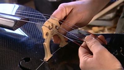 NOW HE SLIDES THE STRINGS
INTO THE GROOVES ON THE BRIDGE. - How It's Made