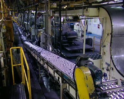 NOW THE CANS MOVE ALONG
UPSIDE DOWN ON THE CONVEYER BELT - How It's Made