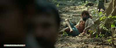 There.. that guy sitting cross legged under
the tree, and smoking a beedi. - Pushpa: The Rise