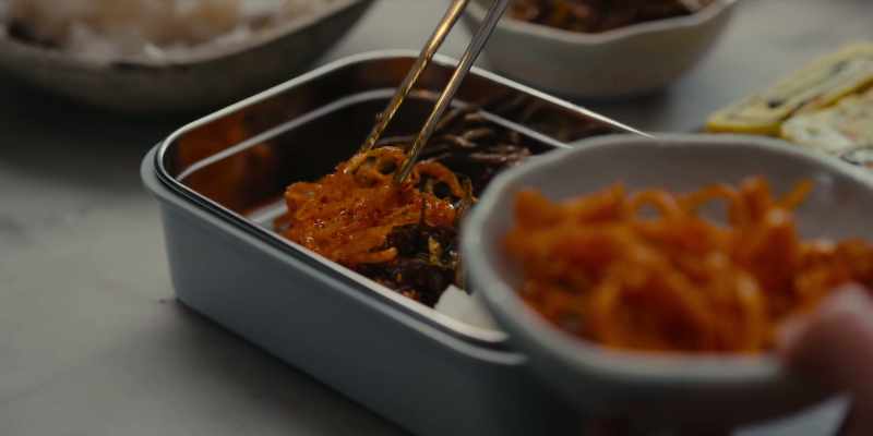 A bento box of rice, kimchi, and dried fish