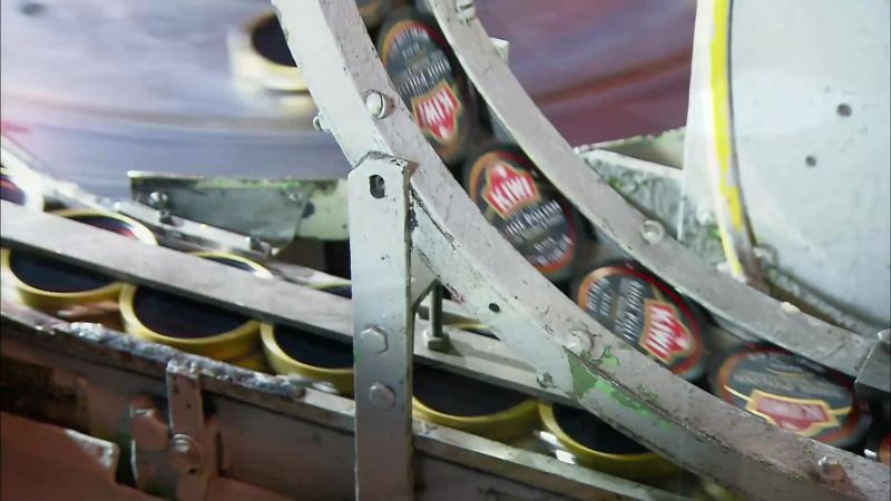 A COMPRESSION WHEEL PRESSES THE LIDS IN PLACE
