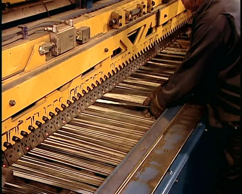 A WORKER FEEDS THOSE WIRE LENGTHS INTO ANOTHER MACHINE