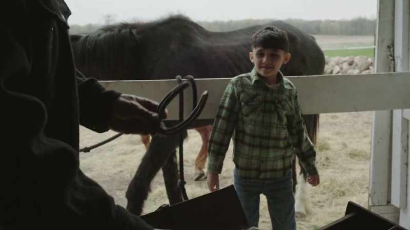 An old man giving a young boy a horseshoe