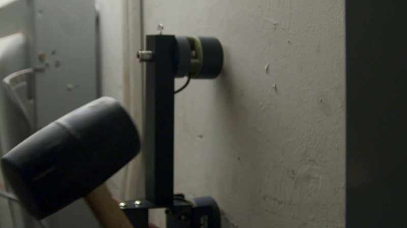 By sending a sound wave into the wall and reading the echo