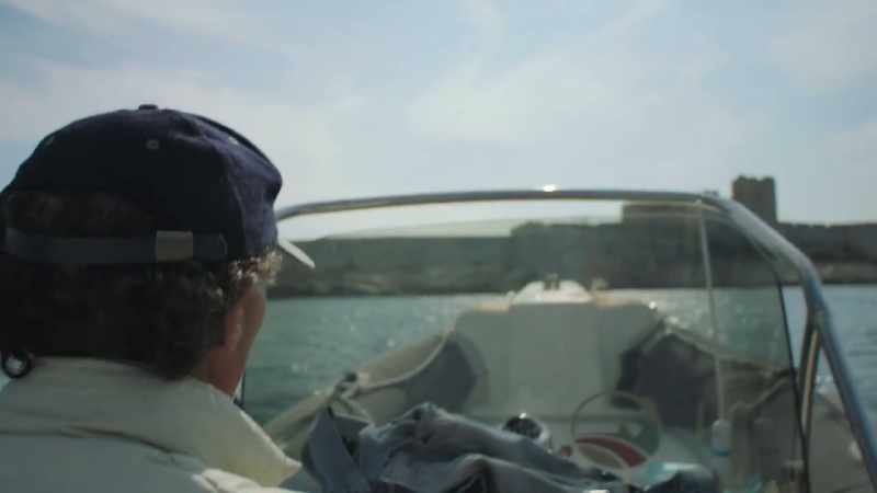 Even when he is escorted by two gendarmes to a boat