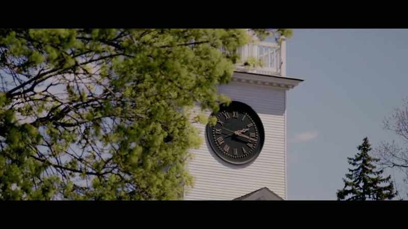 He looks at a steeple with a clock on it