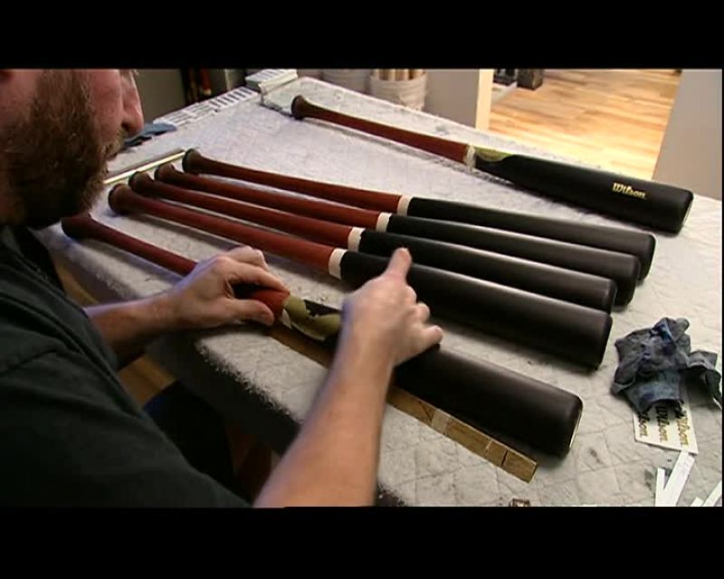 HE PRESSES DECALS ONTO THE BAT