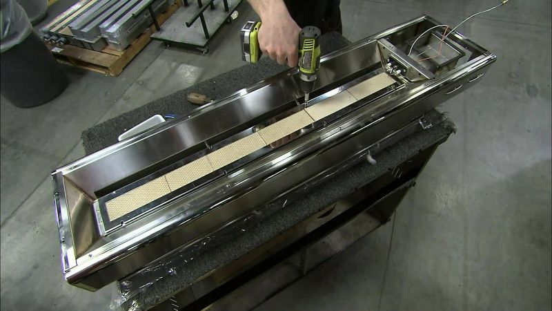 HE SECURES THE BURNER TO THE MAIN ASSEMBLY WITH SCREWS
