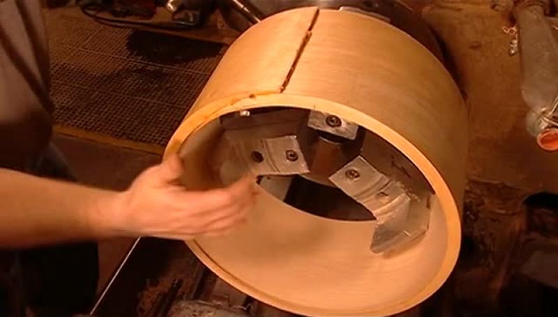 HE TURNS THE DRUM SHELL AROUND TO CUT IT FROM ANOTHER ANGLE
