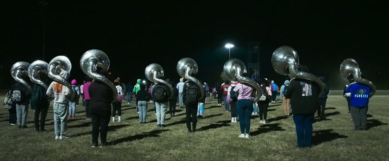 [marching band instruments playing]