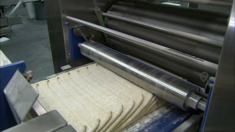 NEXT, ROLLING PINS SQUEEZE THE STACK OF DOUGH