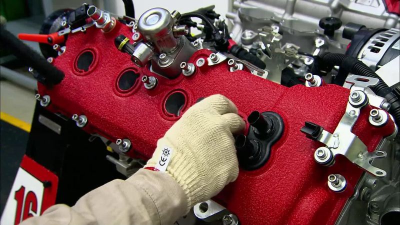 Next, workers position and bolt in the valve cover