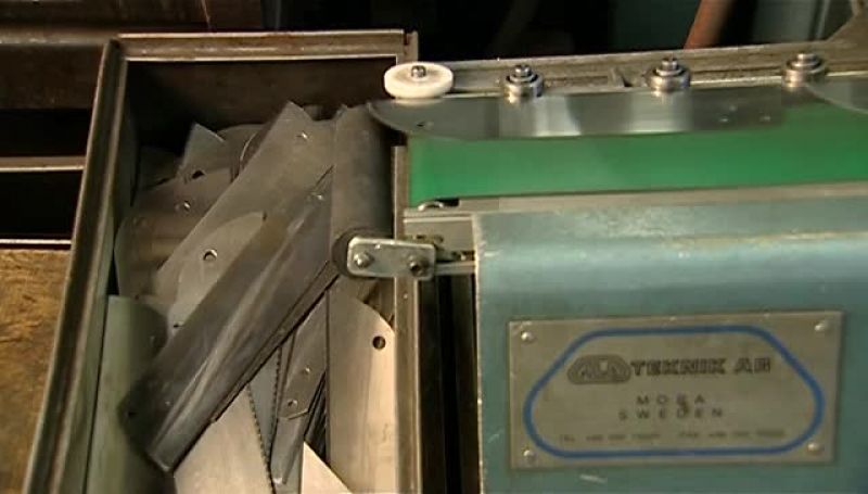 THE BLADES DROP OFF THE CONVEYER INTO A BIN