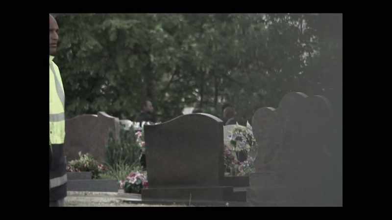 The procession of Rwandans approach the grave here
