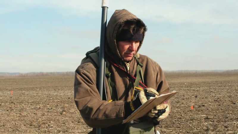 Walking back and forth in a cornfield with a tool