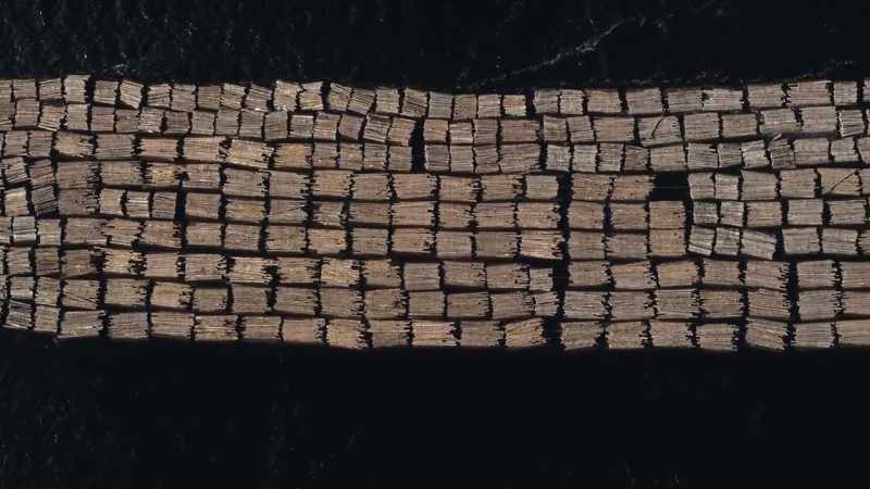 Workers wire thousands of logs together to form